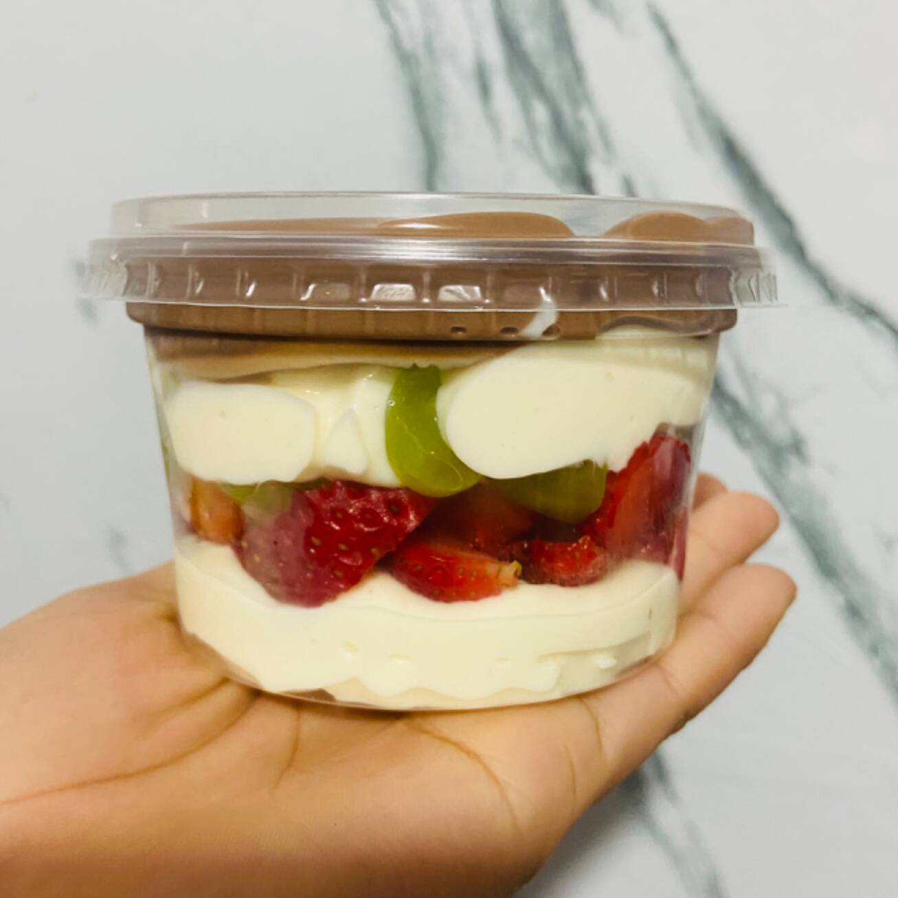 Recheio branco, morango e uvas frescas, finalizado com recheio de chocolate .