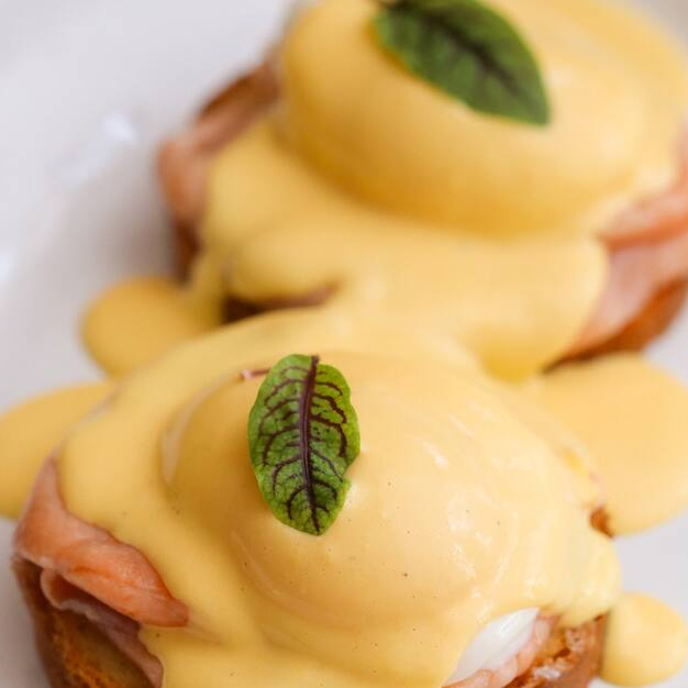 Ovos pochés com molho holandês sobre fatias de brioche.