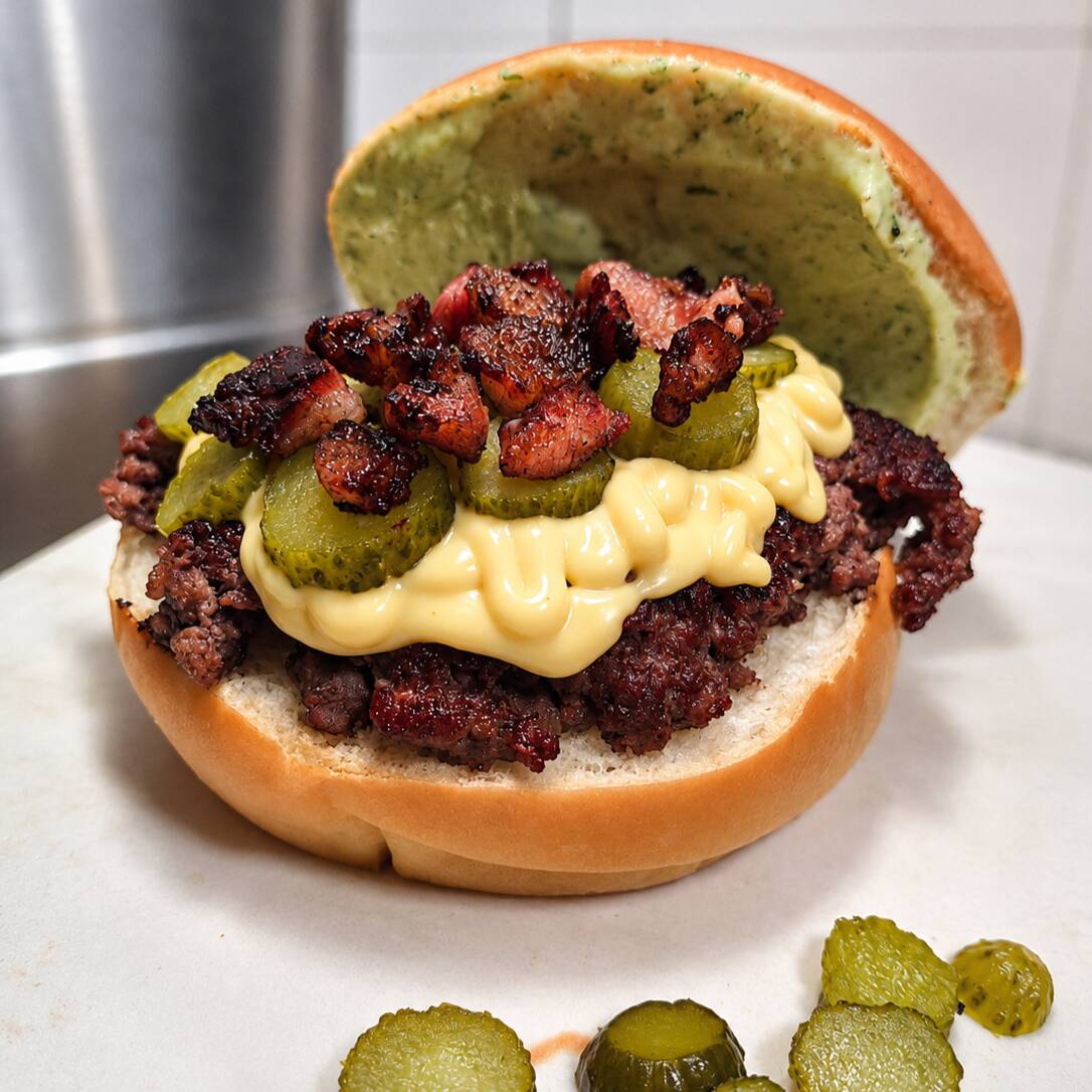 Pão selado, Burguer 140g, cheddar, picles , bacon em cubos, molho do chef/maionese caseira na tampa do pão, acompanha dois saches de molho.