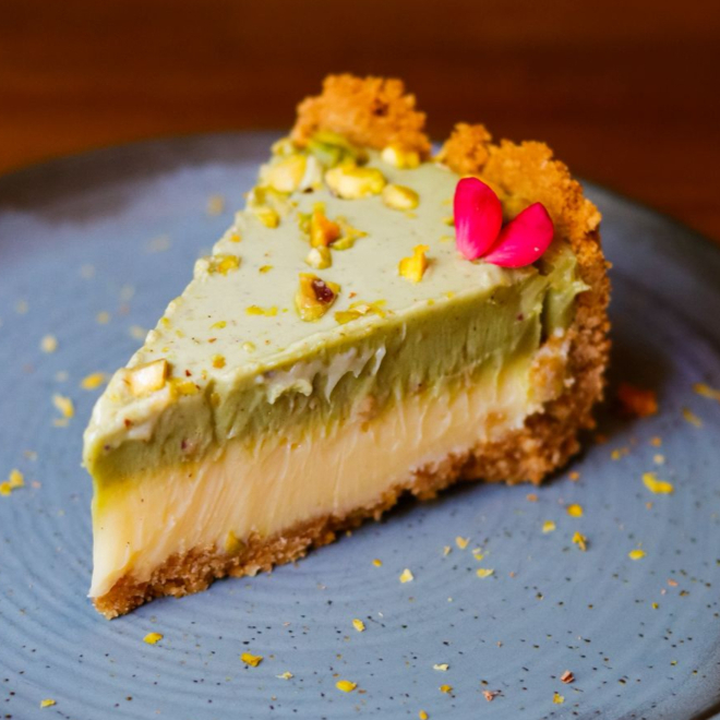 Fatia do nossa maravilhosa torta com base de bolacha, recheio de mousse de limão siciliano e cobertura de creme de pistache fresquinho, feito na casa.