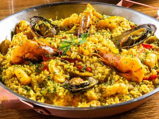 Arroz caldoso com camarão, lula, polvo, peixe e mexilhão, refogado com pimentões, ervilha, especiarias e um leve toque de açafrão. Servidos na paellera. Rico em sabor e apresentação.tamanho do camarão nesse prato: 30g.