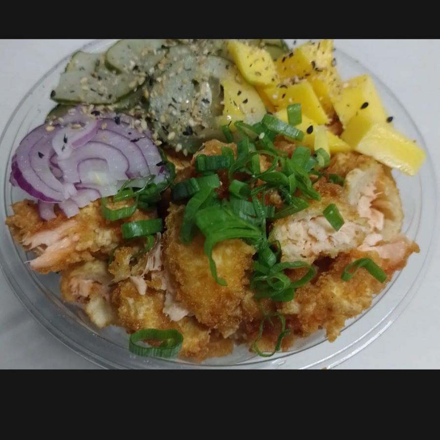 Arroz, Salmão em cubos empanado na panko e frito, Cebola Roxa, Manga, Sunomono (saladinha de pepino agridoce), Cebolinha e Gergelim.