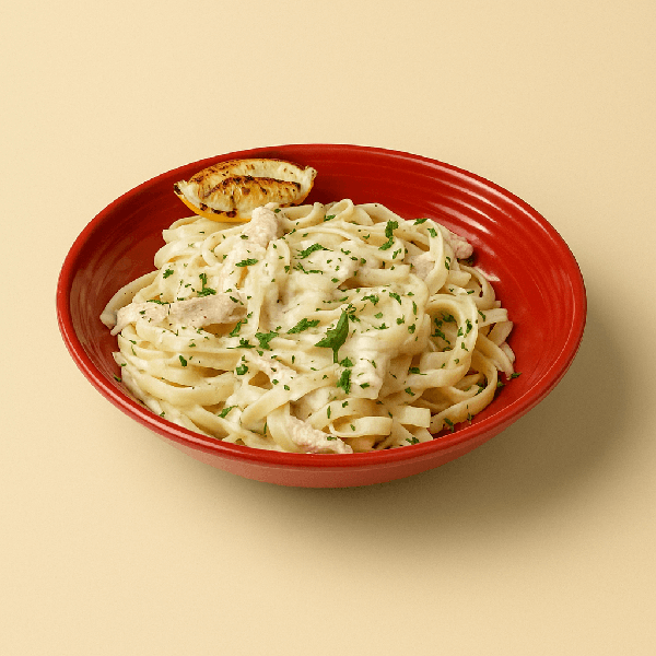Fettuccine ao molho branco com pedaços de frango grelhado. Acompanhado de um pedaço de limão siciliano grelhado.