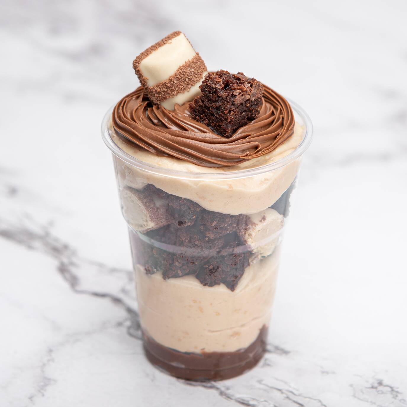 Nosso copo da felicidade vem com camadas de creme de avelã, nosso irresistível creme Bueno inspirado no recheio do Kinder Bueno, brownie tradicional bem molhadinho e pedacinhos de Kinder Bueno no meio pra dar aquele toque especial.
