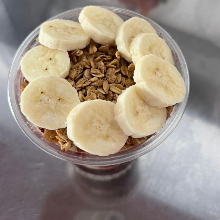 Açai cremoso, acompanhado com granola, leite em pó e leite condensado e banana