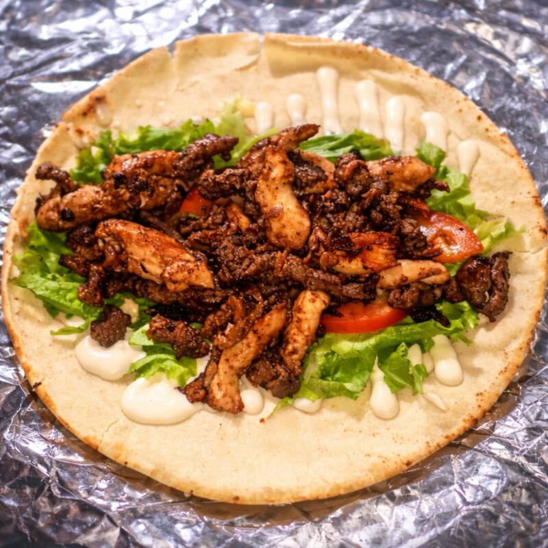 Um mix de carne e frango, servido em pão sírio com molho de alho, alface e tomate.