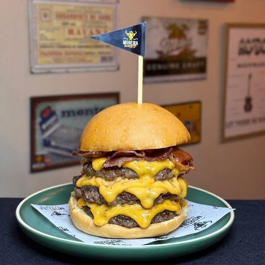 Três Suculentos Burger Angus, Fatias de Queijo Cheddar Americano Entre as Carnes, Fatias de Bacon Crocante, Maionese, Ketchup.
Servido no Pão Levemente Selado
