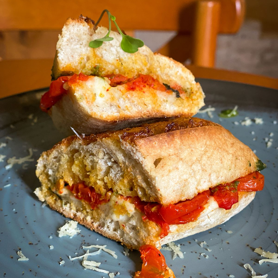 Pão italiano, tipo baguete, de fermentação natural recheado com tomatinhos confitados, manjericão fresco, muçarela de búfula e molho pesto.