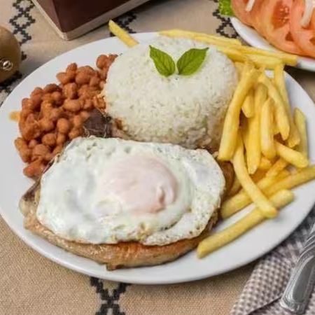 Bife de pernil grelhado com ovo frito, arroz soltinho, feijão temperado, salada fresca e sua escolha entre fritas crocantes ou farofa. Uma versão mini com sabor de prato completo!