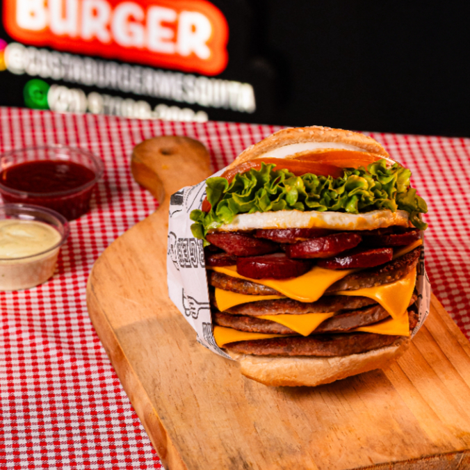 PÃO, 4-CARNES, OVO, 4-FATIAS DE CHEDDAR, CALABRESA, ALFACE, TOMATE E MAIONESE DA CASA.