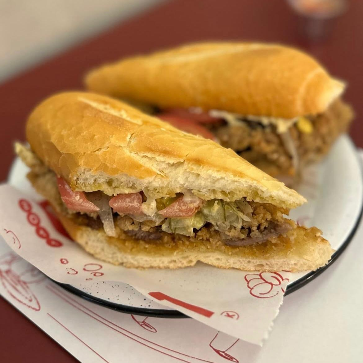 Bife empanado crocante, maionese de zaatar, picles de pepino, cebola tostada e tomate, servido na baguete.