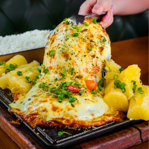 Cupim suculento com crosta crocante de queijo, servido com arroz fresquinho e mandioca cremosa. Um prato completo e delicioso para dividir!