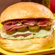 Pão de brioche, maionese verde, smash burguer amassado na chapa com cebola, picles, mussarela e bacon.