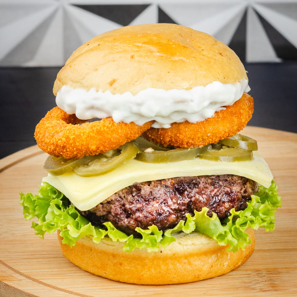 Pão brioche, hambúrguer, mussarela, alface, cebola empanada, molho verde