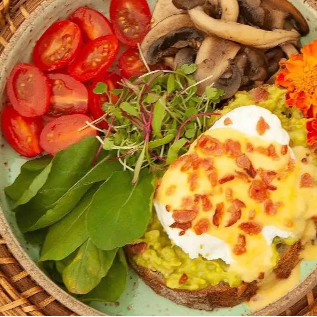 sourdough(torrada) com guacamole, ovo poché, molho hollandaise, farofa de bacon, rúcula, tomate confit e mix de cogumelos