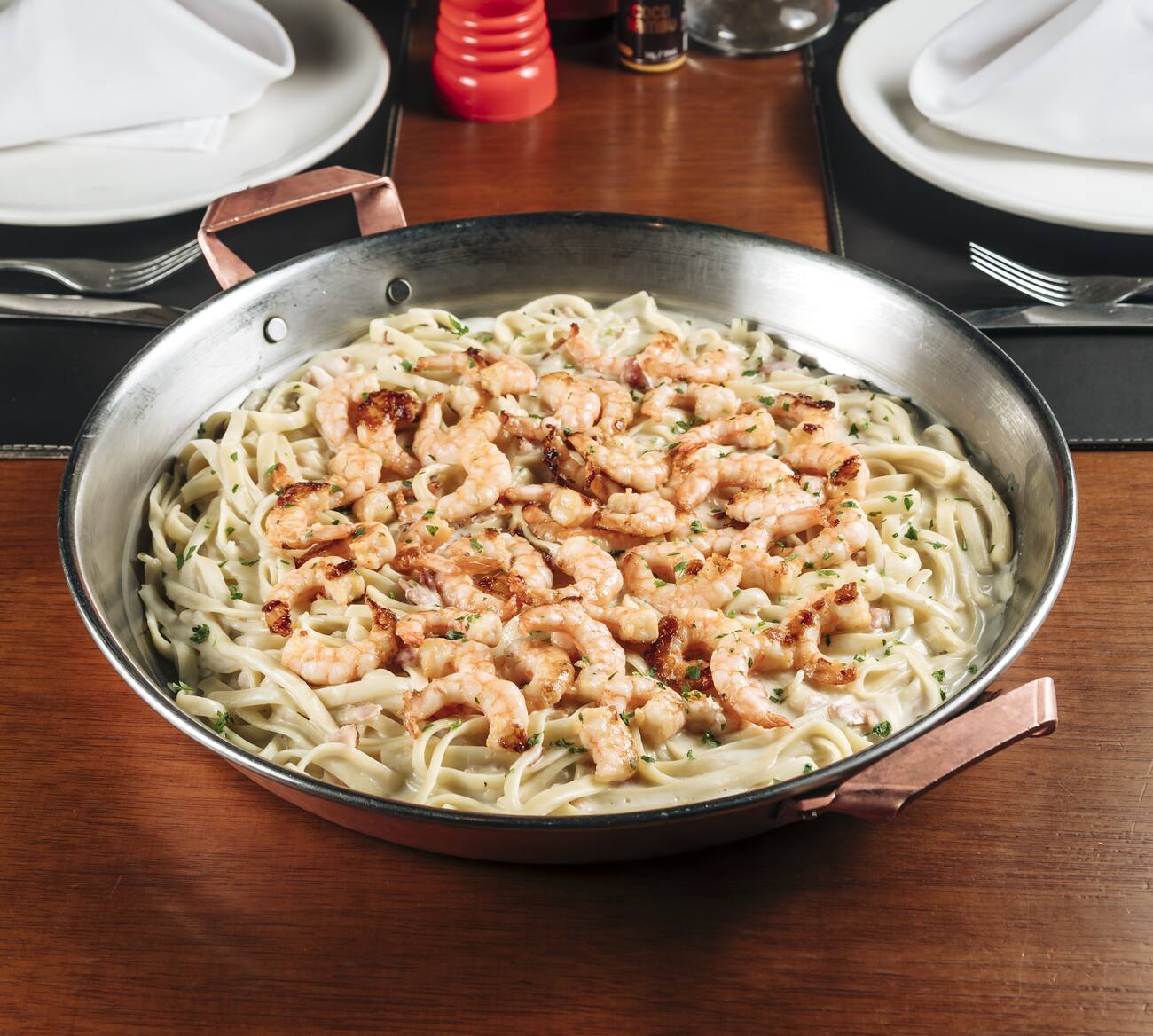 Camarão grelhado sobre fettuccine com molho alfredo e bacon.