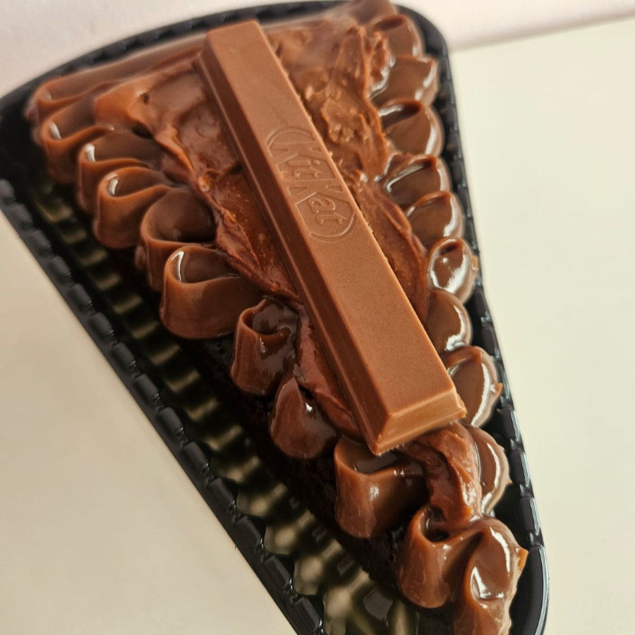 Fatia de brownie chocolatuda, creme de chocolate, crunchy e creamy de kitkat e kitkat para finalizar.