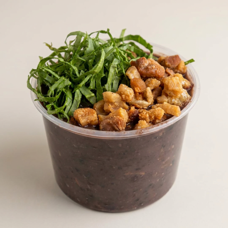 Apresentamos o Feijão Amigo 600ml, da categoria Sopas e Caldos. É uma opção perfeita para quem procura um prato reconfortante e deliciosamente saboroso. O feijão, meticulosamente preparado, ganha um toque especial com a adição de couve fresca e crocante. Para completar, um torresmo de dar água na boca, que traz uma textura inigualável ao prato. Peça sem hesitar, será uma escolha certeira para o seu paladar!