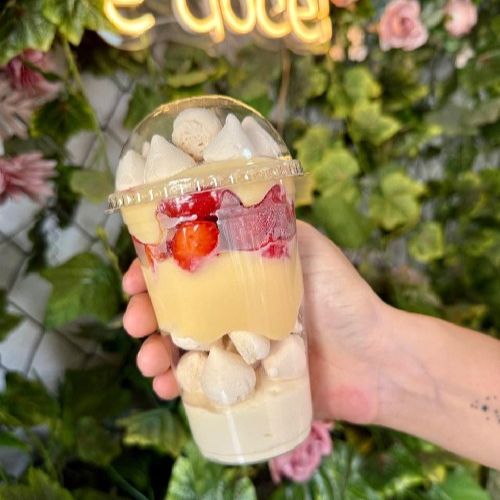 Copo composto por mousse de ninho, suspiros, brigadeiro branco, morangos frescos, brigadeiro branco, finalizado com suspiros.