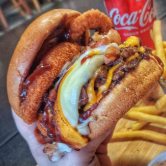 3x carnes smash com crostinha de 180g, explosão de queijos: mussarela, cheddar e requeijão cremoso, bacon em cubos, anéis de cebola e molho barbecue no pão de brioche.