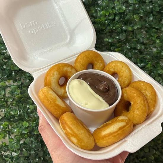 Nossa caixa exclusiva traz 8 mini cake donuts super macios, assados no ponto perfeito. Acompanha um potinho com os nossos sabores campeões de vendas: Brigadeiro Tradicional: Aquele abraço em forma de chocolate. Creme de Ninho: O queridinho, leve e muito cremoso.