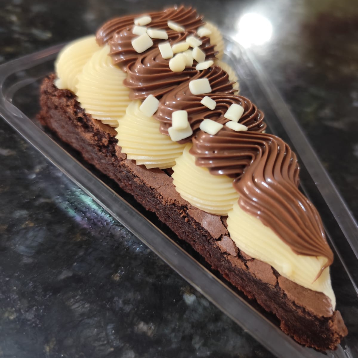 Fatia do nosso brownie com uma massa bem chocolatuda e uma leve casquinha crocante por fora. Generosa cobertura do nosso doce cremoso de leite Ninho com o verdadeiro creme de Nutella e finalizado com granulado de chocolate branco nobre.