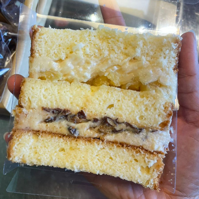 Massa de baunilha, uma camada de recheio de cocada cremosa com abacaxi e uma camada de brigadeiro branco com ameixa. Um clássico