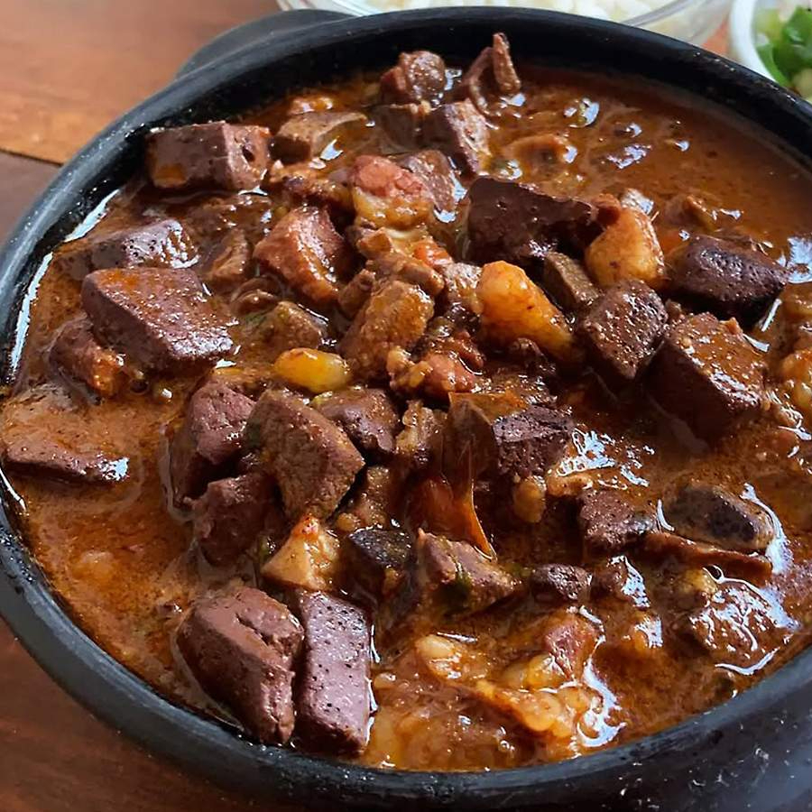 Delicioso Sarapatel cortadinho em pequenos cubos, acompanhado de arroz, e farofinha.