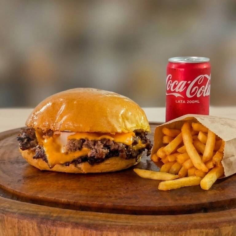 O verdadeiro clássico que nunca falha! Pão brioche super macio, smash burger suculento com crosta crocante e cheddar derretido, acompanhado de batatas bem crocantes e uma Coca-Cola geladinha. A combinação perfeita para matar a sua fome com muito sabor!
