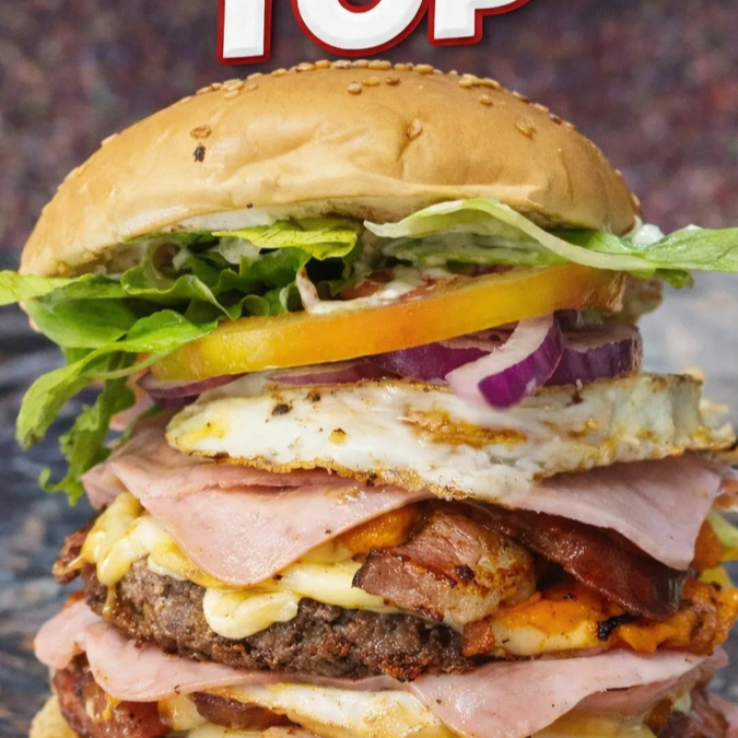 Pão com gergelim, 2 hambúrgueres suculentos, dobro de queijo muçarela derretido, cheddar cremoso, dobro de bacon crocante, dobro de calabresa, dobro de presunto, 2 ovos, alface fresquinha, cebola roxa, tomate selecionado e maionese da casa. Gigante, completo e super recheado, feito pra quem tem fome de verdade! 🤤🔥