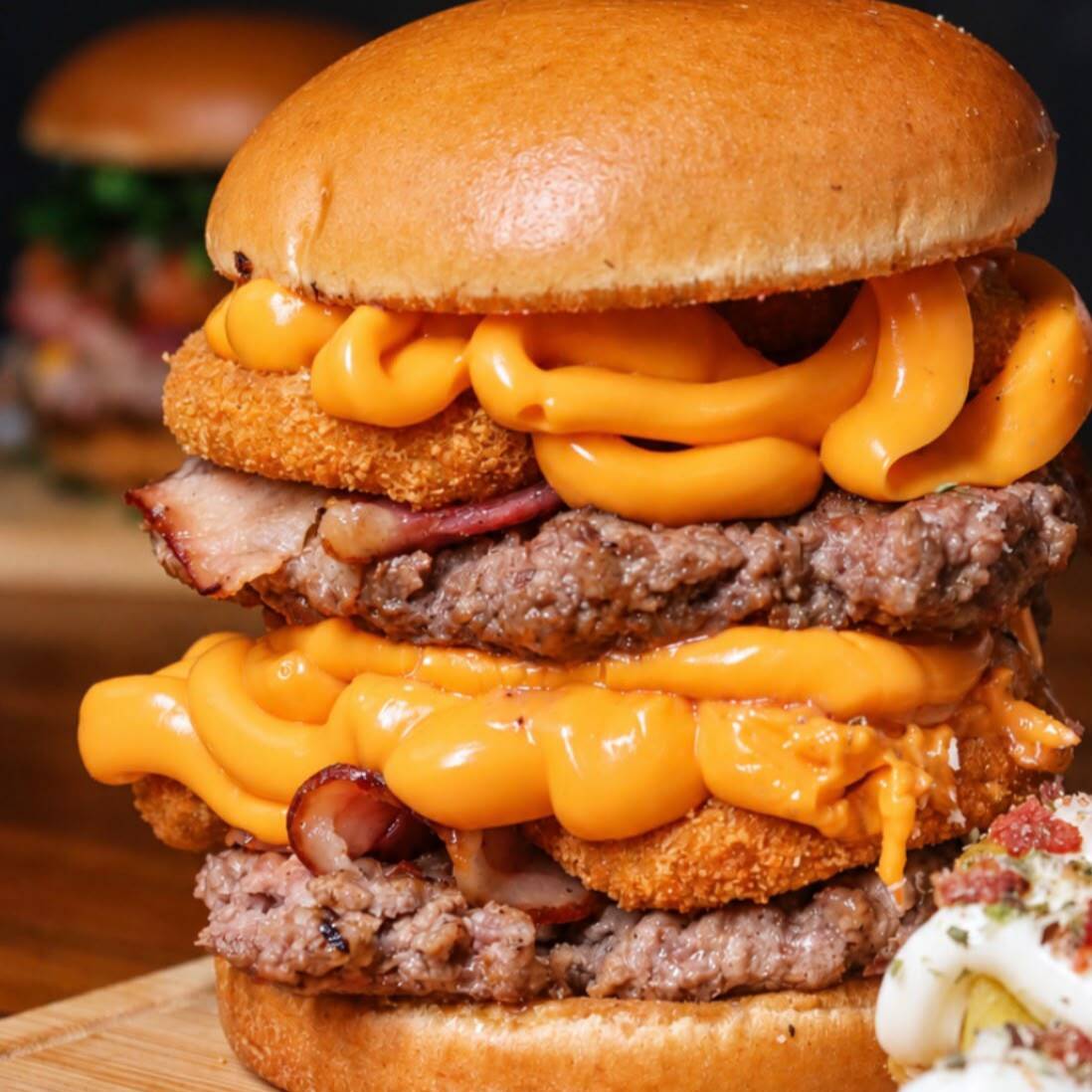 O Melhor Cheddar da Sua Vida
Construído em camadas perfeitas: Pão de brioche na manteiga, dois blends premium (240g total) intercalados com cheddar derretido, bacon duplo crocante e onion rings douradas.
🎁 Cortesia: Ganhe Batata Rústica + Super Maionese Temperada.