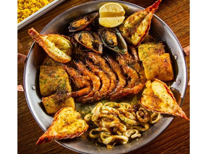Indescritível prazer do mar nordestino. Lagosta, camarão, mexilhões, peixe e lula grelhados com molho provençal. Acompanha arroz de açafrão.Tamanho do camarão nesse prato: 30g.
