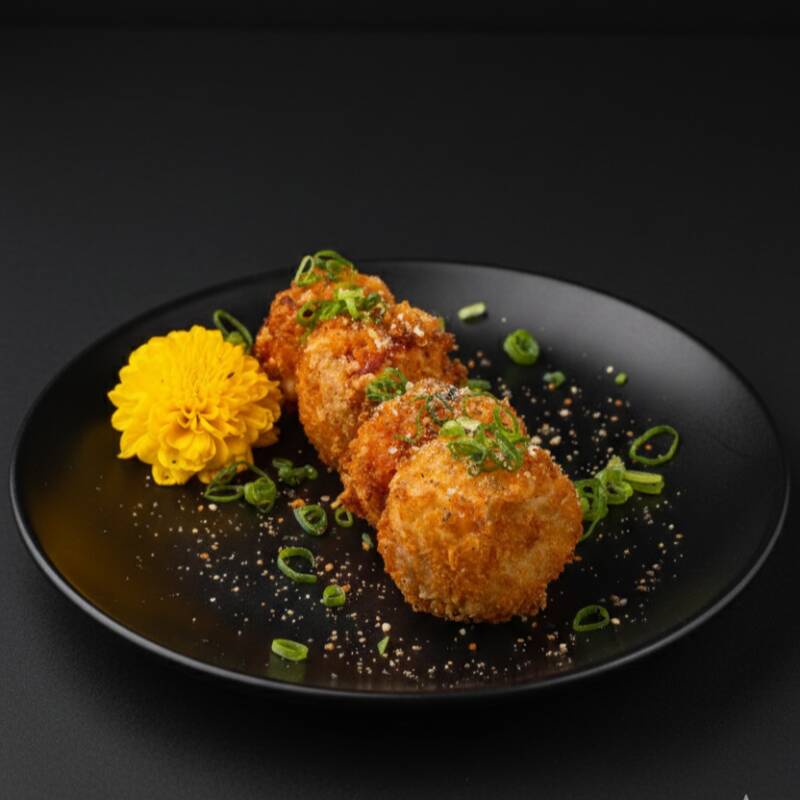 Creme cheese envolvido por lâmina de kani, empanado na farinha panko, finalizado com cebolinha e gergelim moído.