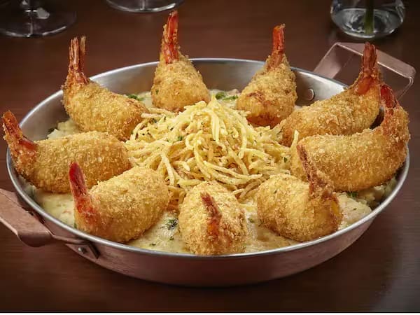 9 camarões empanados, recheados com queijo Catupiry, servido sobre cremoso arroz com camarão, ervilhas e presunto envolvido com molho branco. Gratinado com queijo mussarela. Acompanha batata palha.