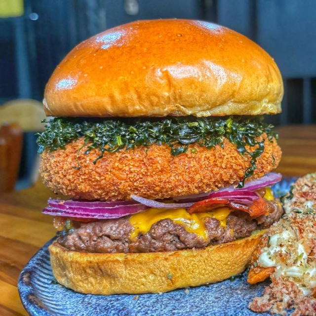 VMega Catupiry Empanado (150g) 👑
O burger perfeito para quem ama cremosidade e crocância extrema.
Pão de brioche na manteiga, hambúrguer premium de 150g, cheddar derretido, bacon, cebola roxa, couve crispy sequinha e o astro da casa: um generoso Catupiry empanado e explosivo.
🎁 Grátis: Batata Rústica + Super Maionese Temperada de tirar o fôlego.