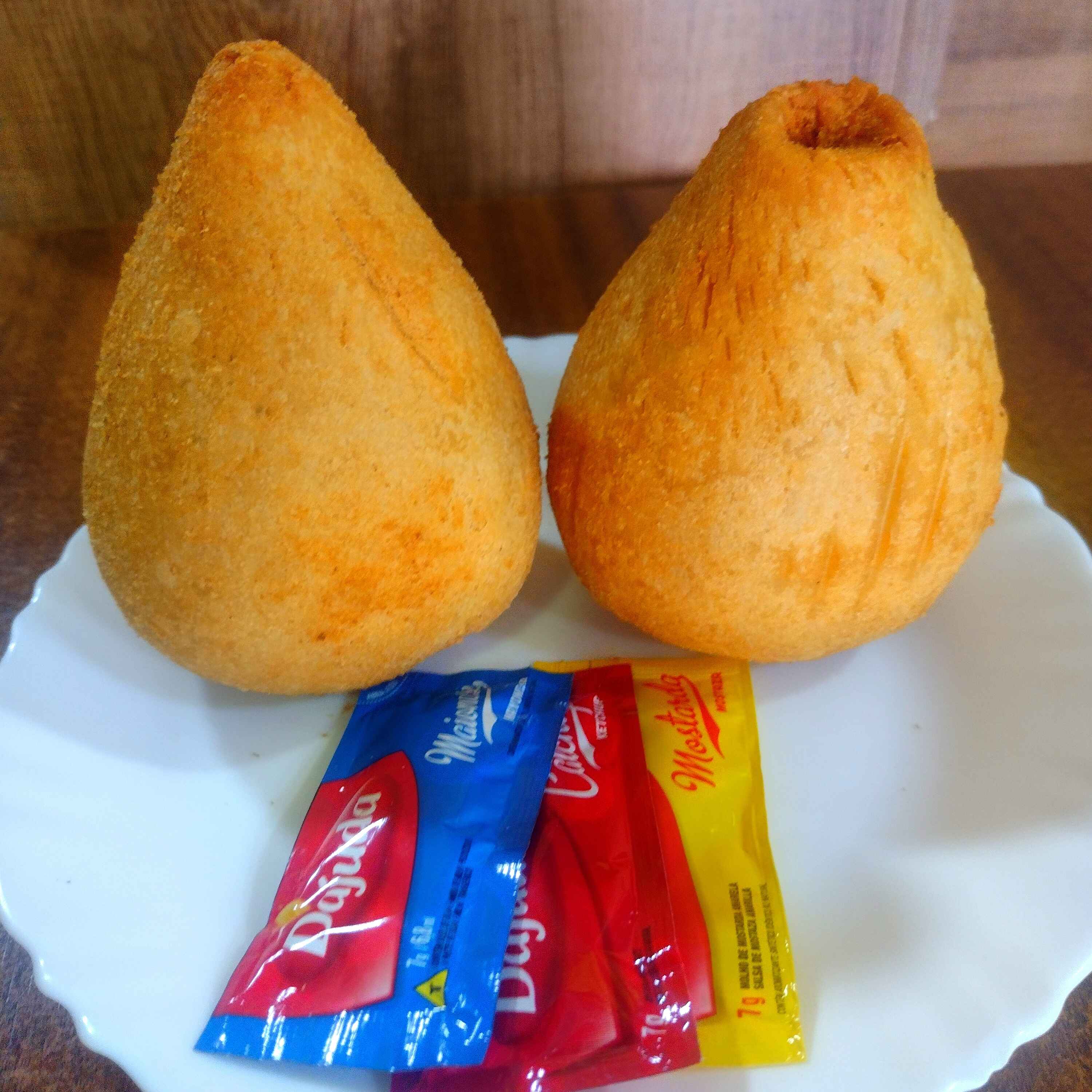 Coxinha recheada com frango desfiado e temperos especiais, envolta em uma massa crocante.