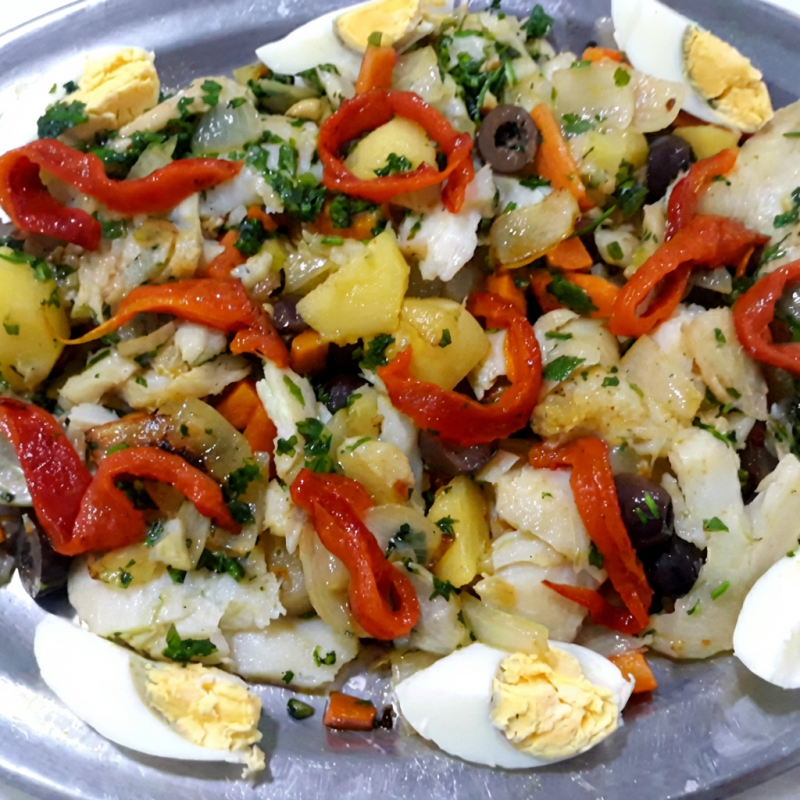 Delicioso bacalhau porto Gadus Morhua, especialmente desfiado na casa, refogado em azeite extra virgem, com cebola, salsa, batata, cenoura azeitonas e pimentão vermelho, acompanhado de ovos cozidos. Pode ser servido como salada também.