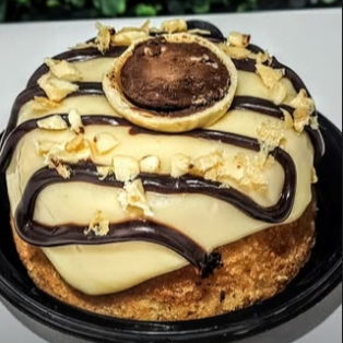 a melhor sobremesa gourmet no precinho: bolo mini vulcão ouro branco. TAMANHO DE REFERÊNCIA: PALMA DA MÃO/ 10CM. Massa branca fofinha com recheio de ninho cremoso, com pedaços de ouro branco e gotas de chocolate. Finaizado com riscos de chocolate cremoso e meio ouro branco esfarelado.