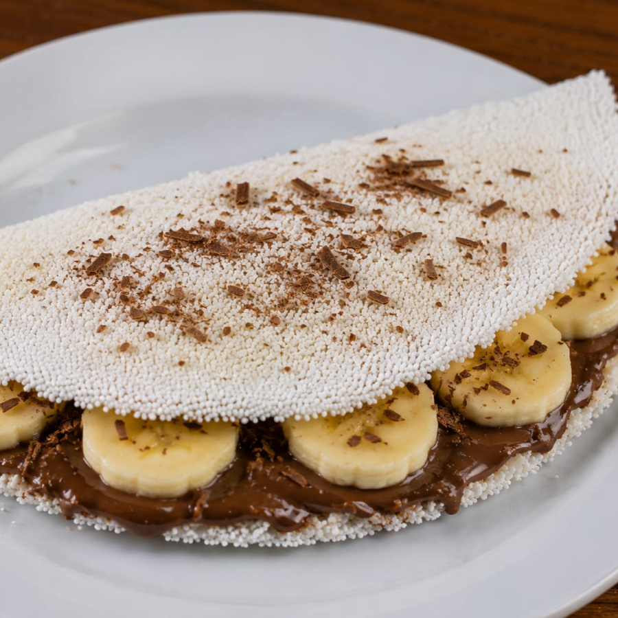 Uma combinação irresistível que vai conquistar o seu paladar! Tapioca preparada na hora, recheada com banana fresquinha e o delicioso chocolate Suflair derretido, unindo a doçura natural da fruta à cremosidade do chocolate em uma experiência simplesmente apaixonante.