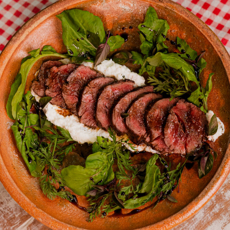 Escalope de filé mignon grelhado à perfeição (ao ponto ou mal-passado) e fatiado em leito de creme de ricota, folhas frescas, cebola roxa tostada e redução de balsâmico, acompanhado de fatias de pão Italiano de Fermentação Natural.