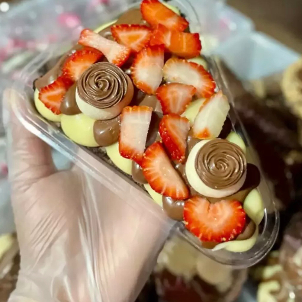 Brownie com cobertura de brigadeiro de ninho, Nutella, pedaços de morangos, e dois brigadeiros gourmet de ninho com Nutella.