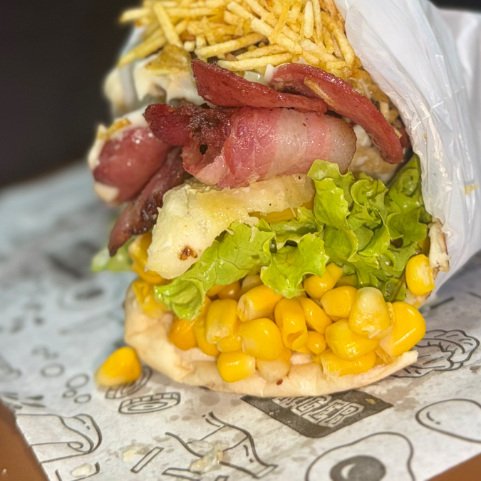 Pão, hamburguer, presunto, mussarela, calabresa, bacon, alface, tomate, milho, batata, catupiry e abacaxi.