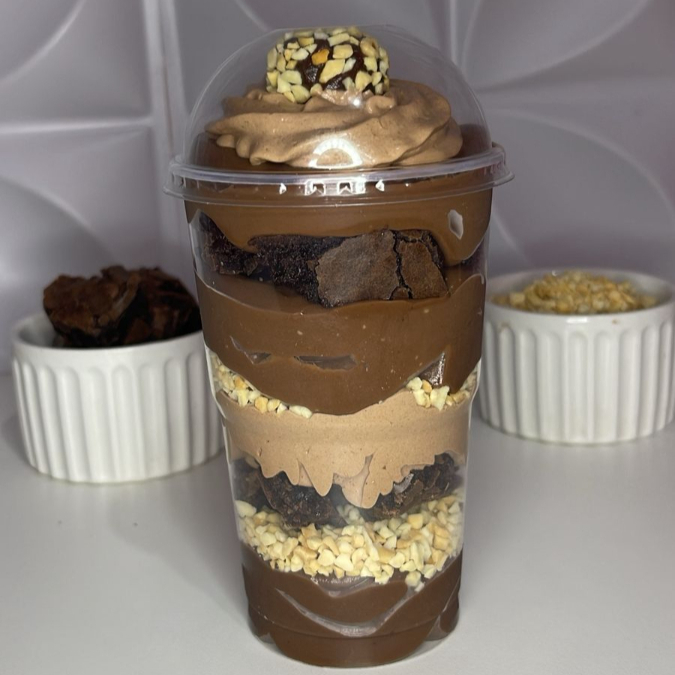 Uma sobremesa sofisticada e irresistível! Montado em camadas generosas, esse copo traz: Brigadeiro 50% cacau para um sabor intenso e equilibrado Crocância do amendoim triturado Pedaços macios de brownie artesanal Mousse de chocolate cremoso que derrete na boca Finalização com um brigadeiro Ferrero na decoração, trazendo luxo e elegância .Cada colherada é uma experiência única, combinando cremosidade, crocância e o inconfundível sabor do Ferrero Rocher. Perfeito para adoçar momentos especiais ou presentear quem você ama.