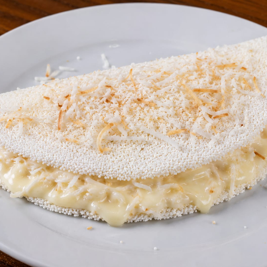 Tapioca de Coco com Leite Condensado
Recheada com coco ralado selecionado e finalizada com uma generosa camada de leite condensado, proporcionando uma combinação irresistível de sabor, cremosidade e aquele gostinho caseiro que conquista a cada mordida.