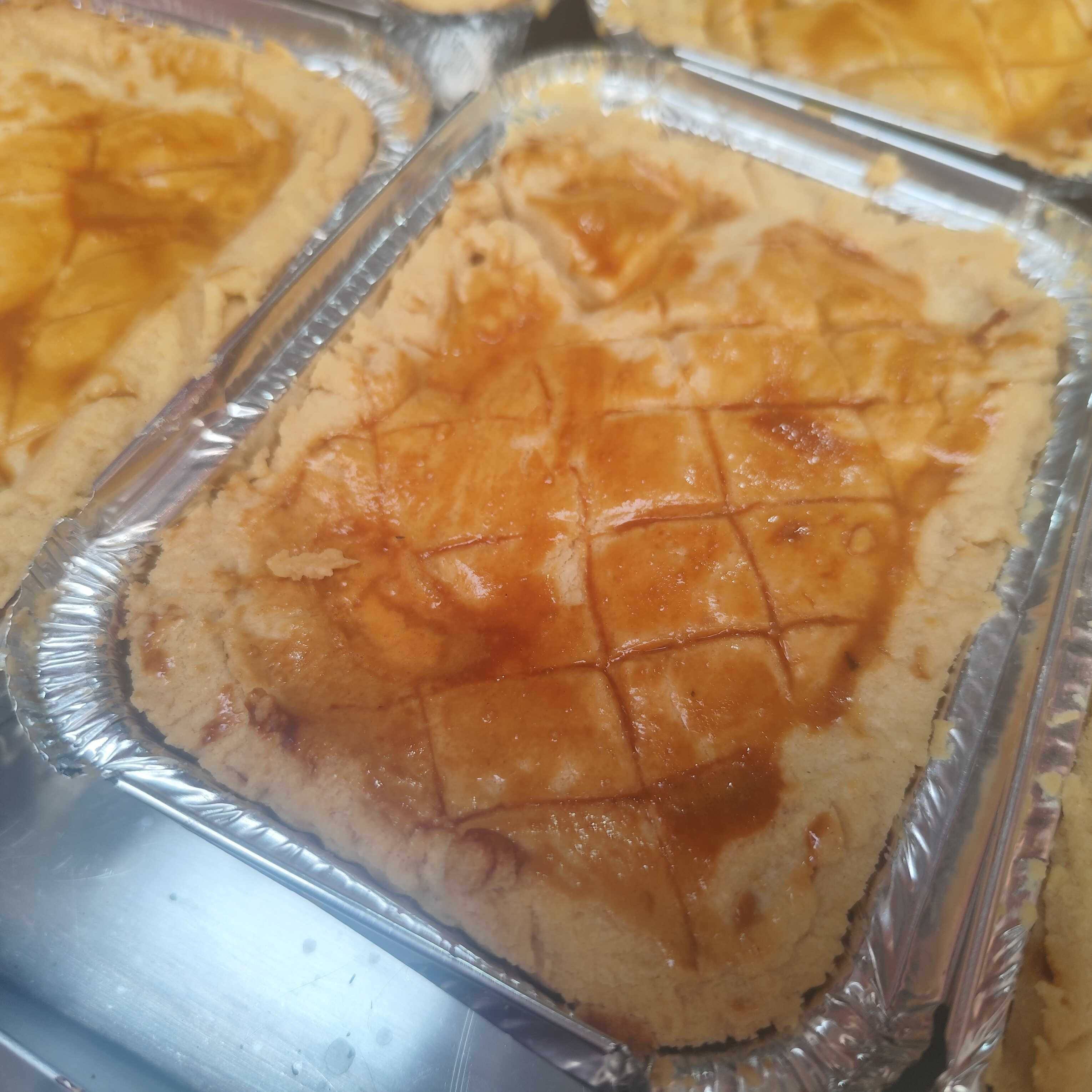 Servidas em prato claro, fatias de empadão de massa dourada com recheio cremoso e denso, decoradas com folhas verdes no topo e na lateral.