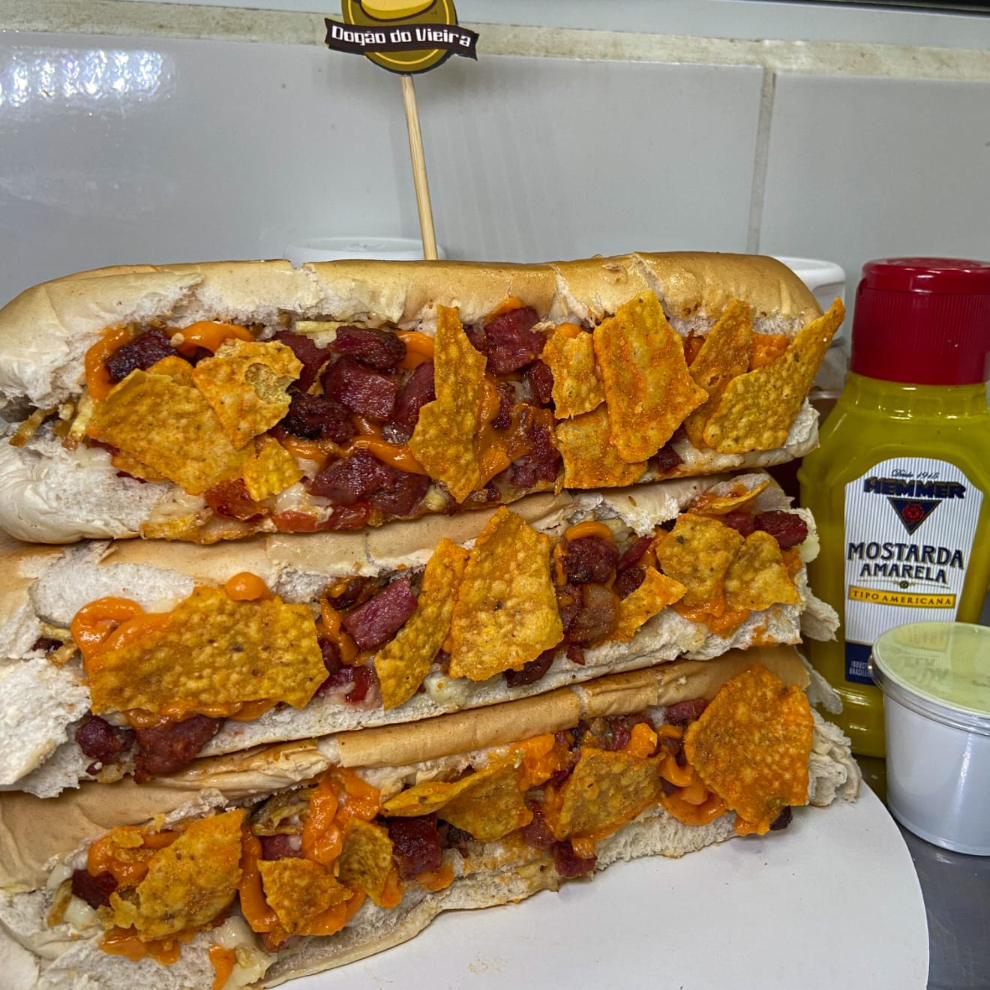 Três pães especial recheado com duas salsichas, tomate, milho, maionese caseira, Cheddar, bacon e nachos. Uma combinação saborosa que vai satisfazer seu paladar.