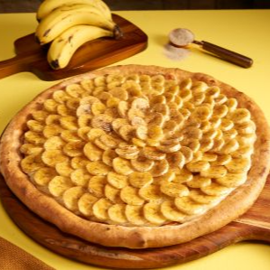 "Irresistível! Bananas frescas caramelizadas no forno sobre nossa massa tradicional com creme de confeiteiro, açúcar e canela. Tudo assado junto para garantir cremosidade máxima e um aroma inconfundível. Quentinha e doce na medida certa!"