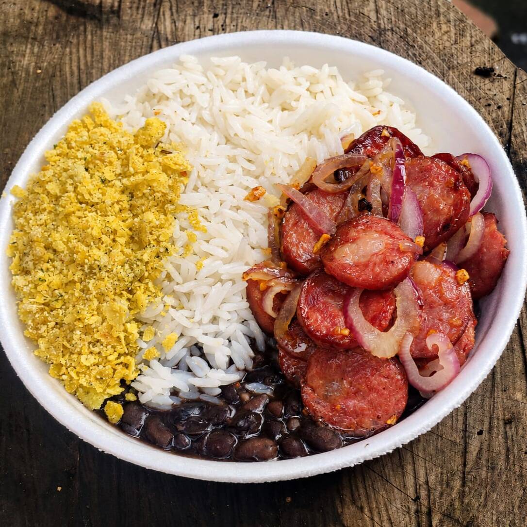 Calabresa acebolada dourada no ponto, envolvida por cebola roxa levemente caramelizada, acompanhada de arroz soltinho e feijão cremoso. Uma combinação clássica, saborosa e feita para matar a fome com aquele gostinho de comida caseira.