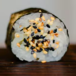 Enrolado de alga e arroz com couve-flor tostada, pimentão amarelo, creme de castanha e cebolinha finalizado com mix de gergelim.