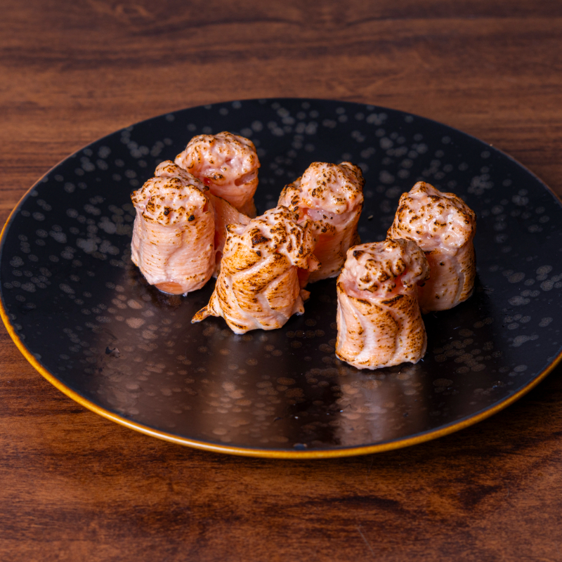 Lâmina de salmão envolto de arroz, e por cima pasta de curry e cream cheese.